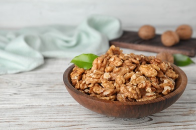 Plate with tasty walnuts on wooden table. Space for text