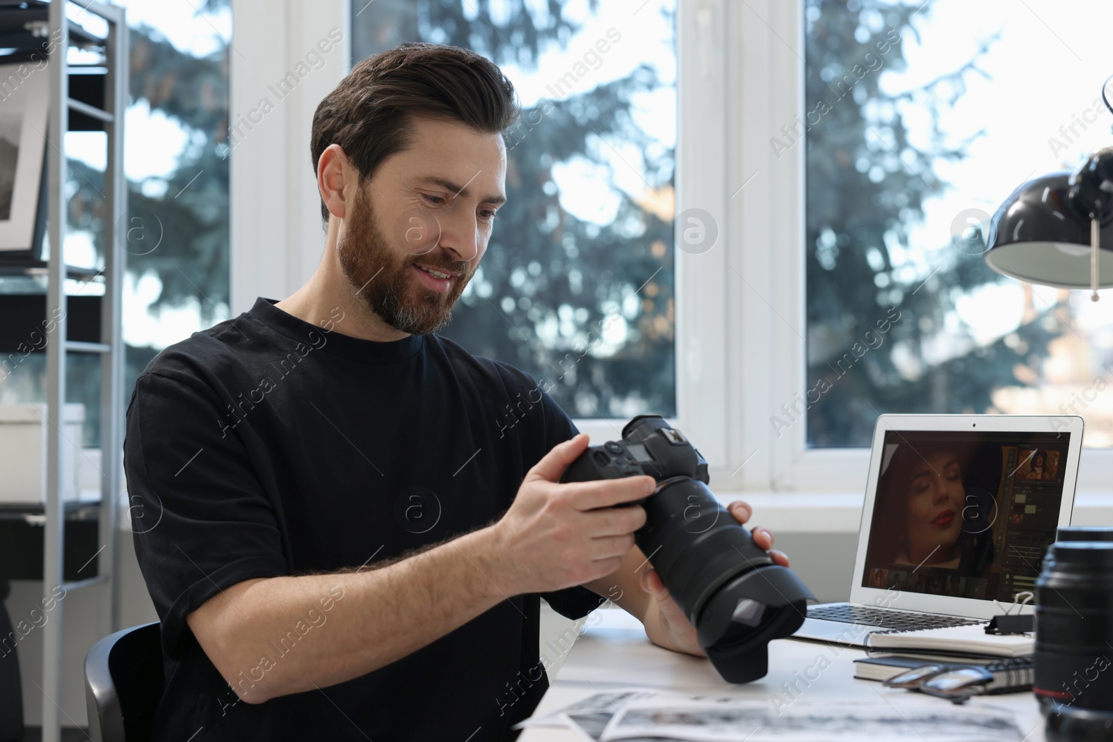 Photo of Professional photographer with digital camera at table indoors