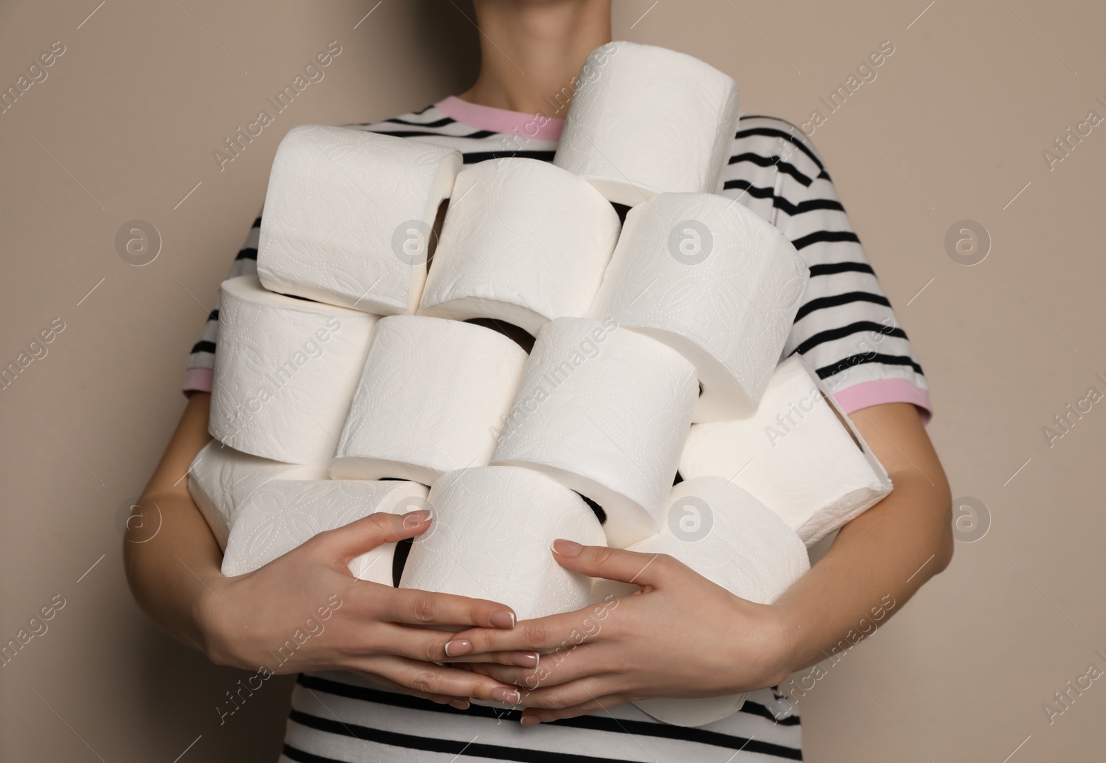 Photo of Woman with heap of toilet paper rolls on beige background, closeup