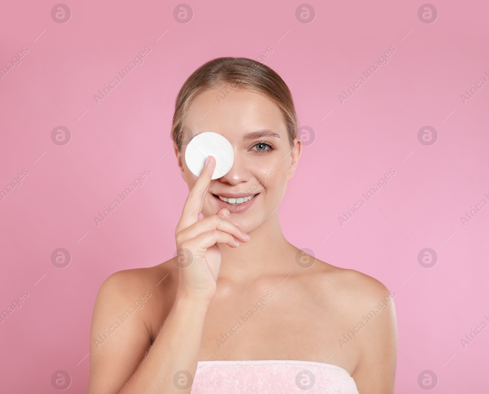 Photo of Beautiful young woman with cotton pad on pink background