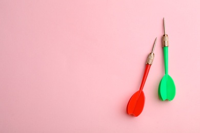 Photo of Plastic dart arrows on pink background, flat lay with space for text