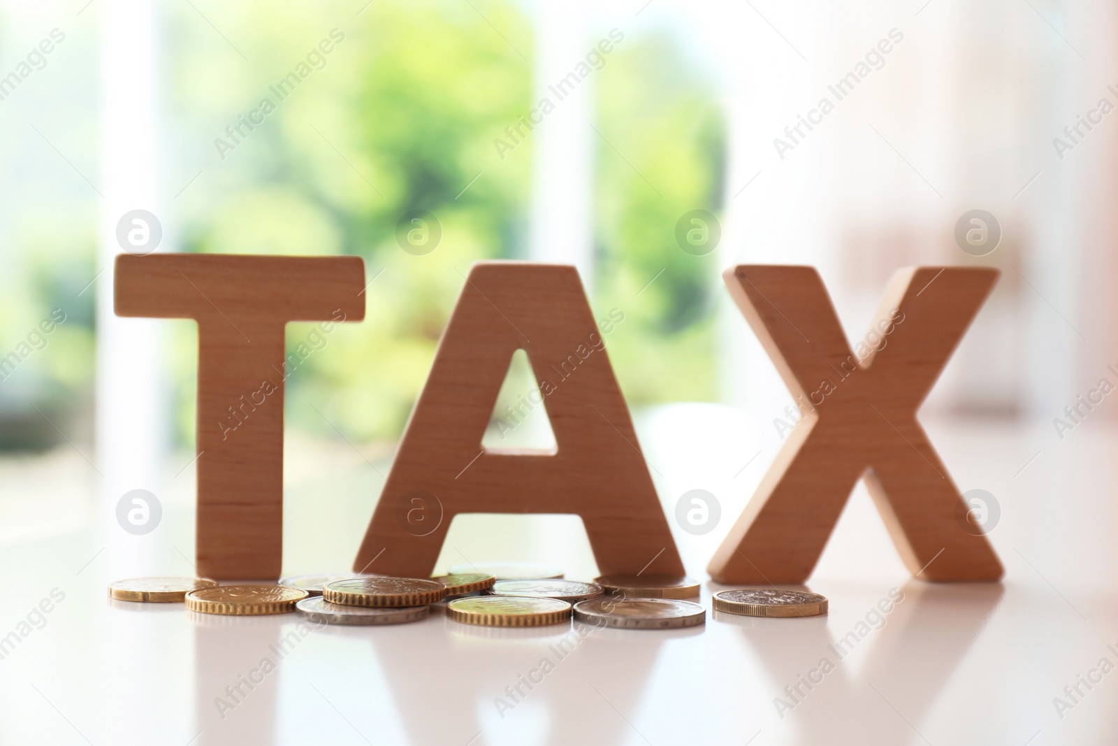 Photo of Word TAX made of letters and coins on table against blurred background