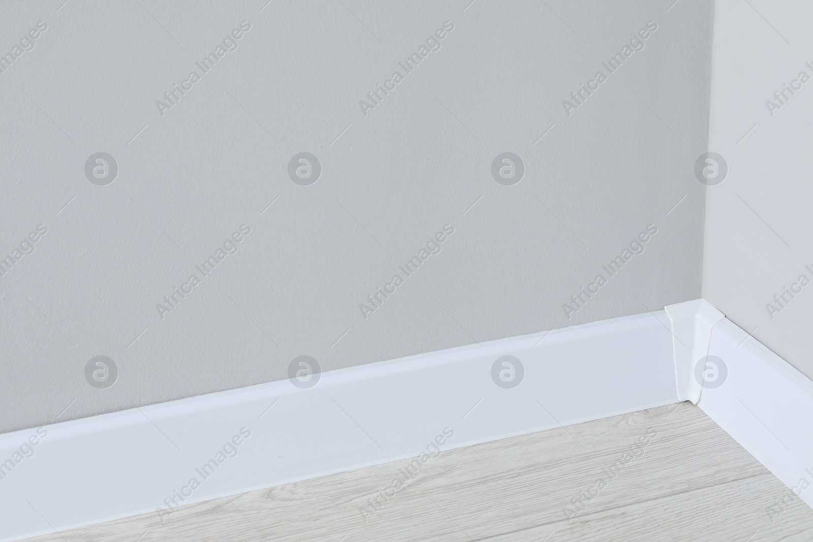 Photo of White plinth with connector on laminated floor near wall indoors, closeup