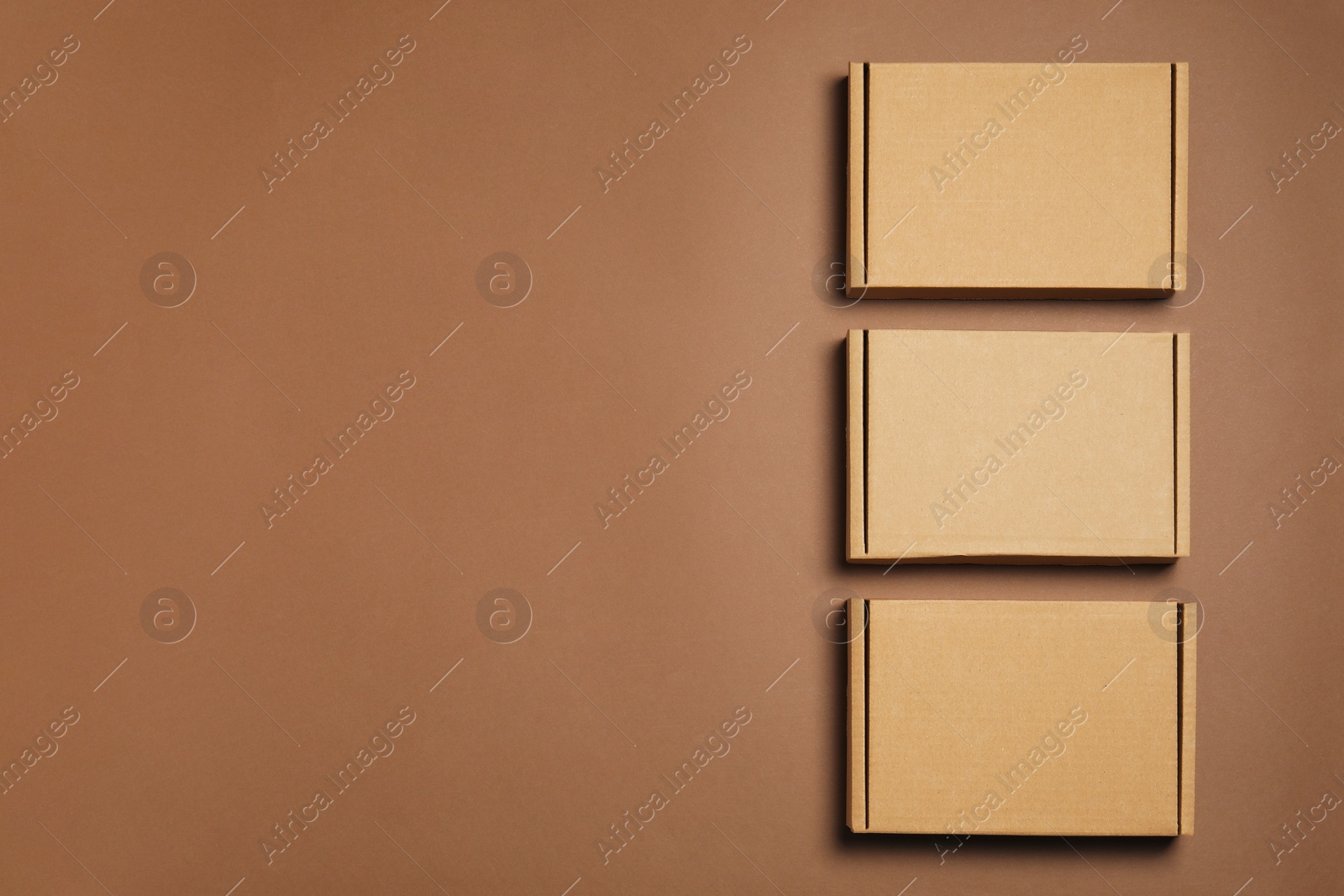 Photo of Many closed cardboard boxes on brown background, flat lay. Space for text