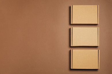 Photo of Many closed cardboard boxes on brown background, flat lay. Space for text