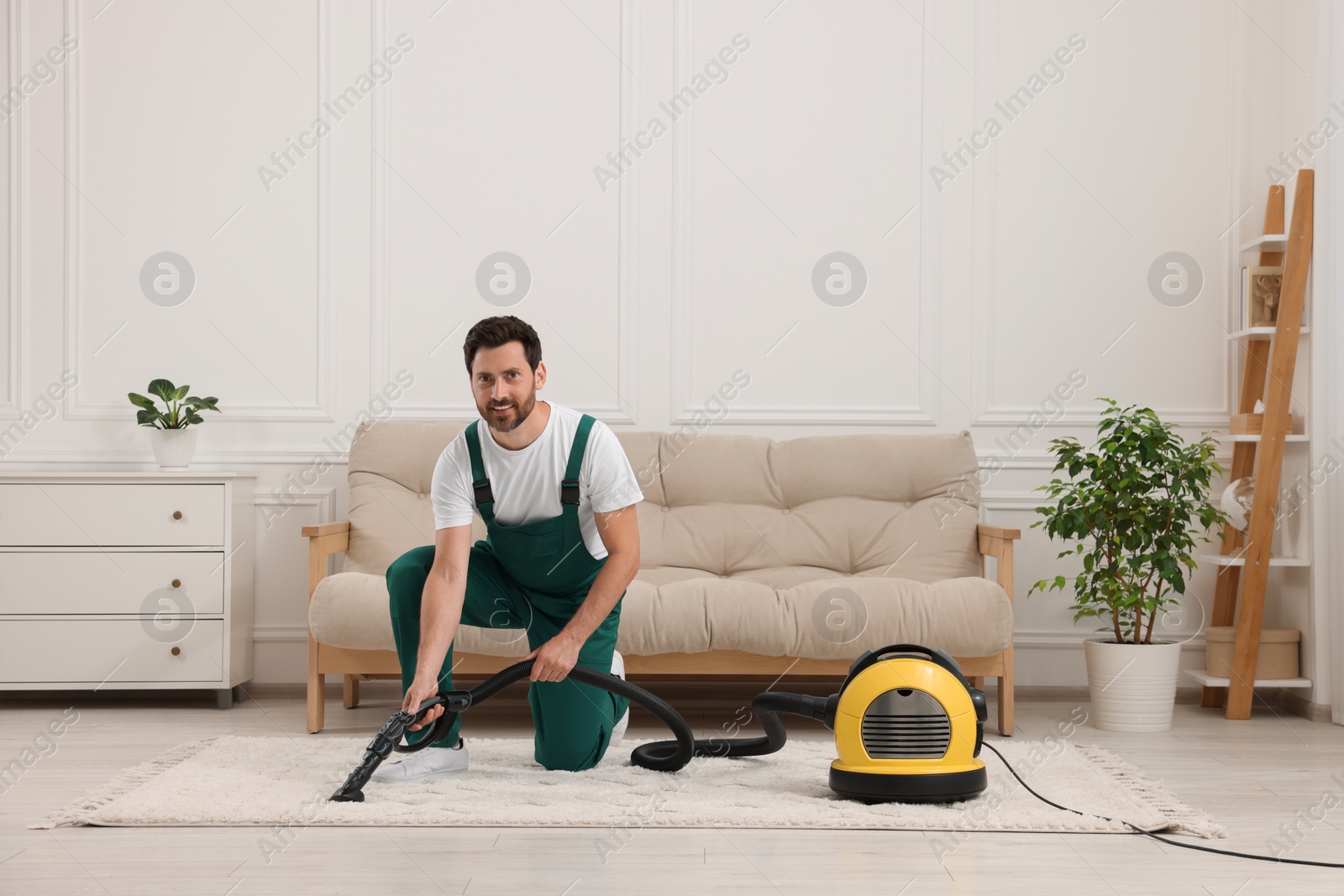 Photo of Dry cleaner's employee hoovering carpet with vacuum cleaner in room