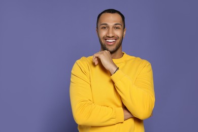 Portrait of happy African American man on purple background. Space for text