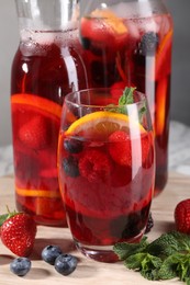 Photo of Delicious refreshing sangria and berries on board, closeup view