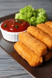 Photo of Plate of cheese sticks with sauce on table, closeup