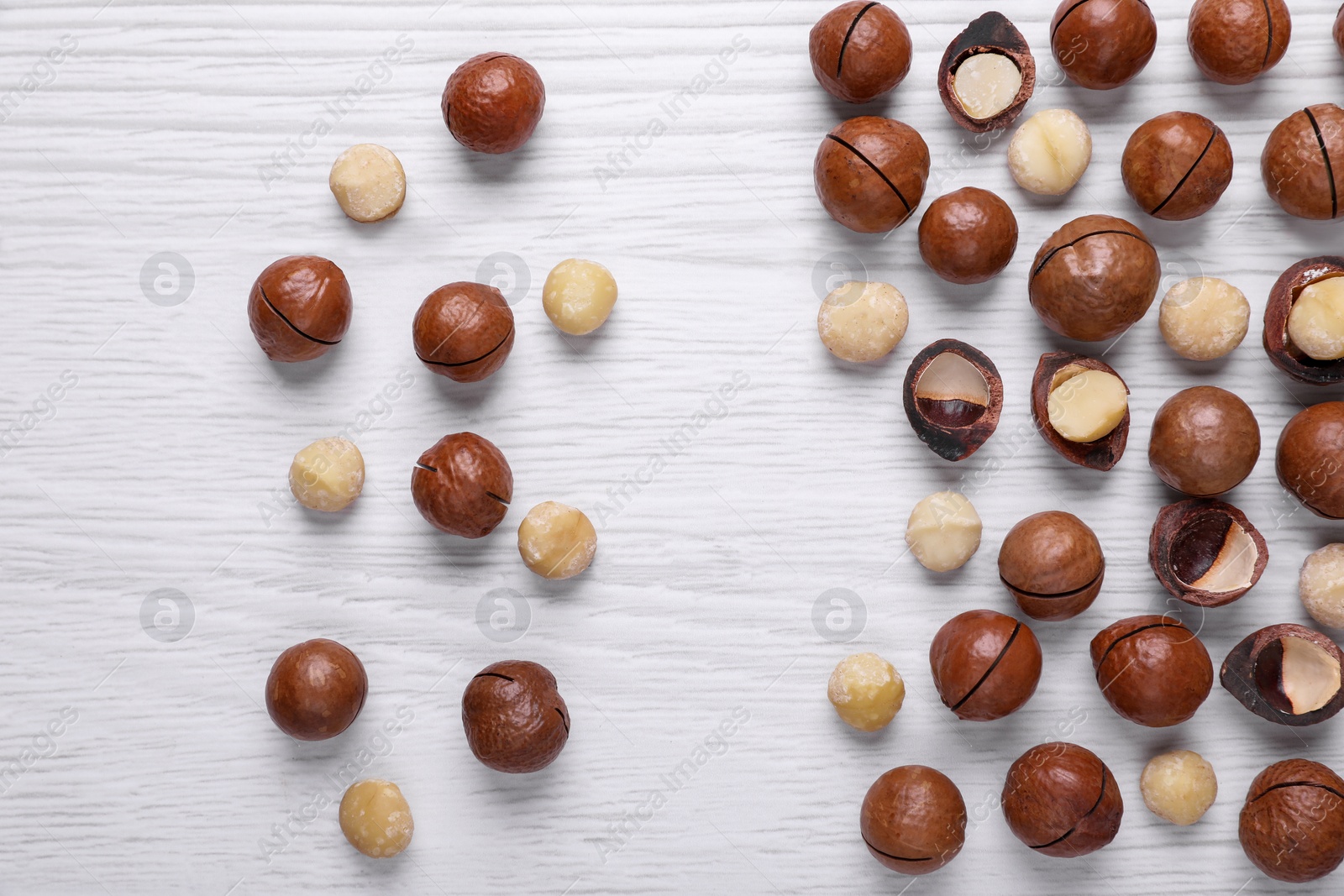 Photo of Delicious Macadamia nuts on white wooden table, flat lay