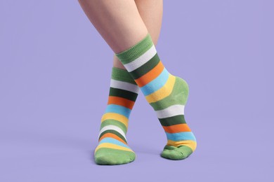 Photo of Woman in stylish colorful socks on violet background, closeup