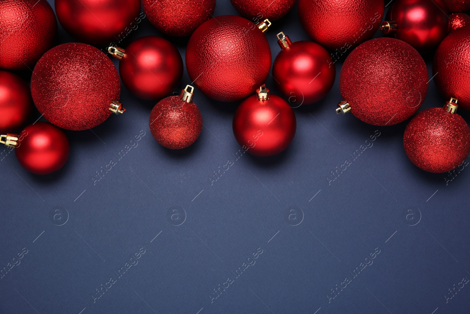 Photo of Red Christmas balls on dark blue background, top view. Space for text