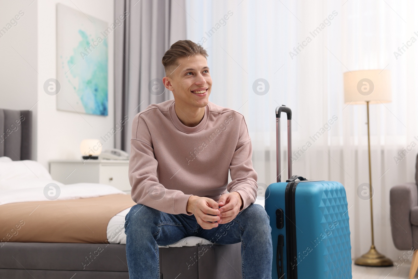 Photo of Smiling guest relaxing on bed in stylish hotel room