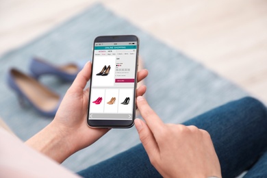 Woman shopping online via smartphone indoors, closeup