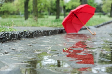 Photo of Open umbrella on city street, closeup. Rainy day