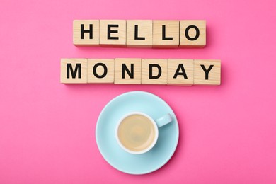 Photo of Wooden cubes with message Hello Monday and cup of coffee on pink background, flat lay