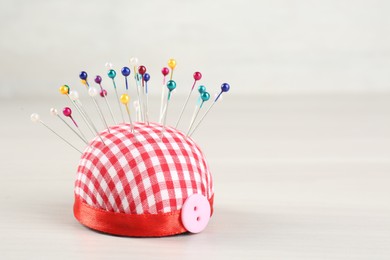Photo of Pin cushion with button on light beige table, closeup