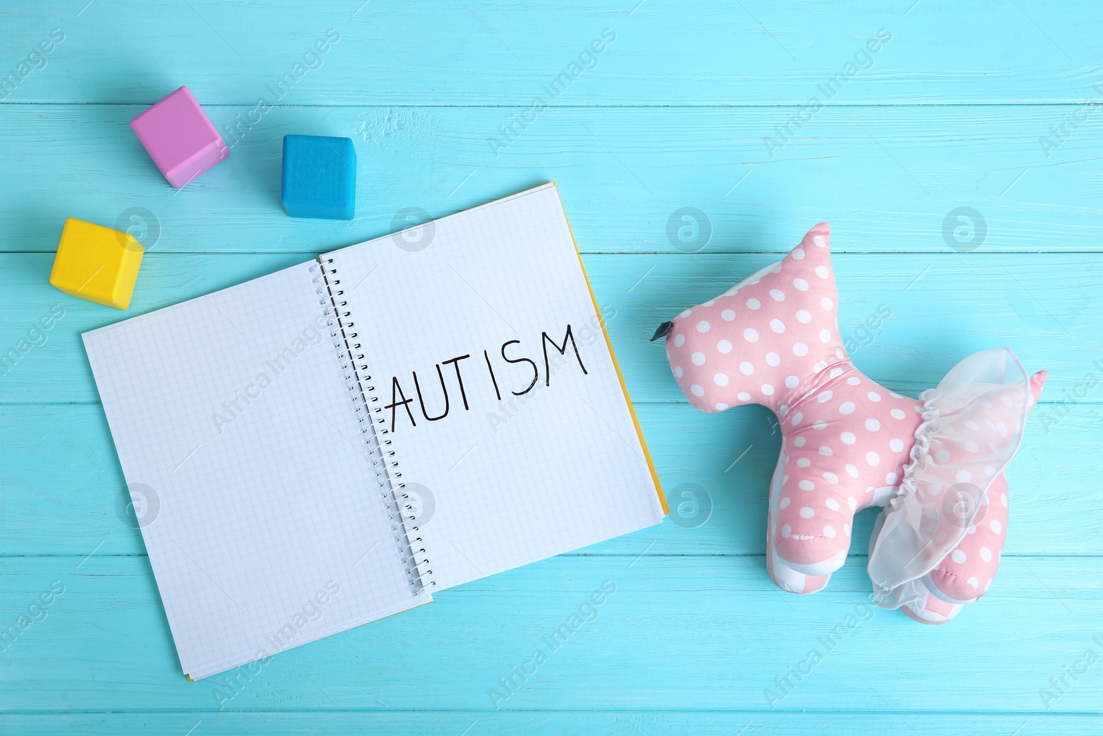 Photo of Notebook with word AUTISM and toy dog on color background, top view