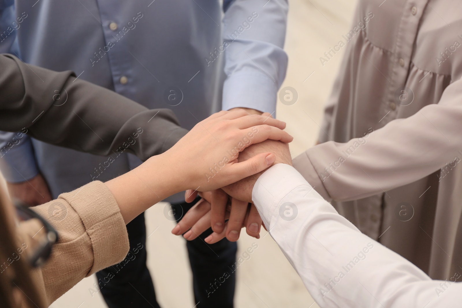 Photo of Group of people holding their hands together on blurred background, closeup