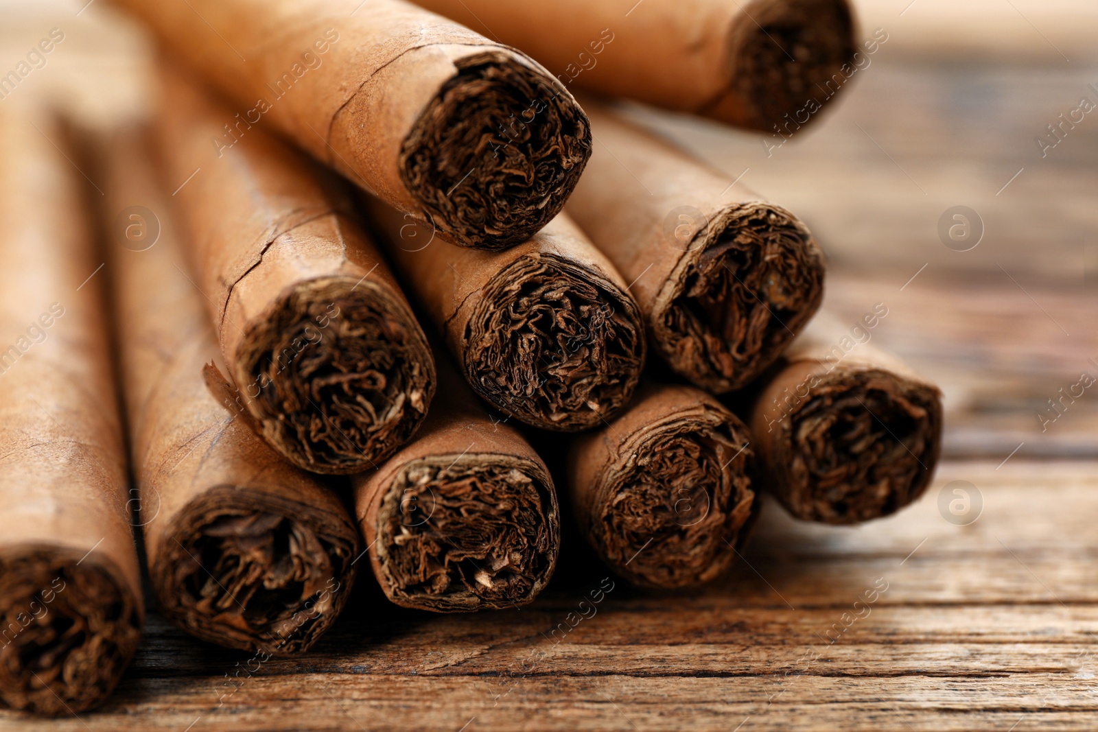 Photo of Cigars wrapped in tobacco leaves on wooden table, closeup