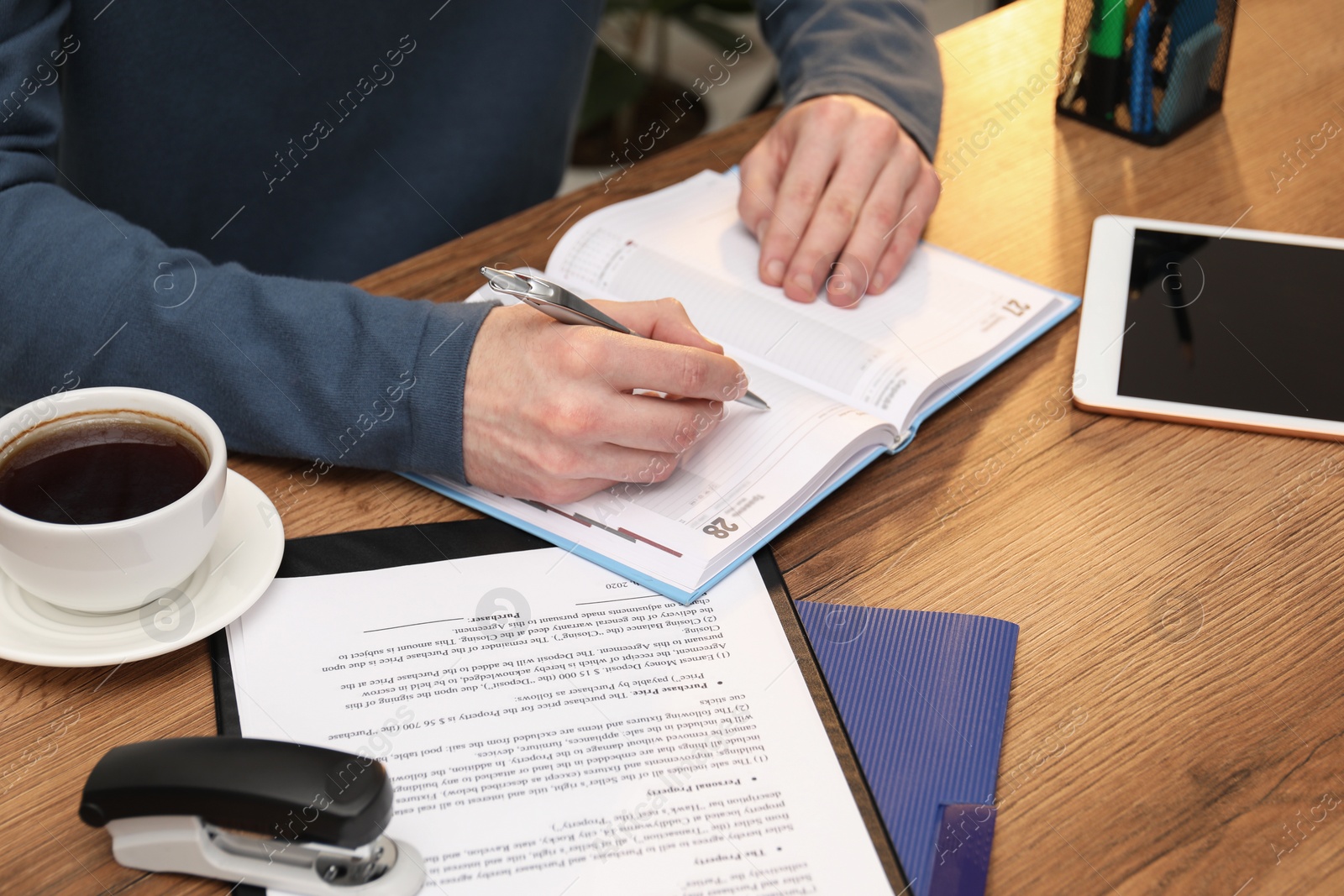 Photo of Man taking notes at wooden table, closeup