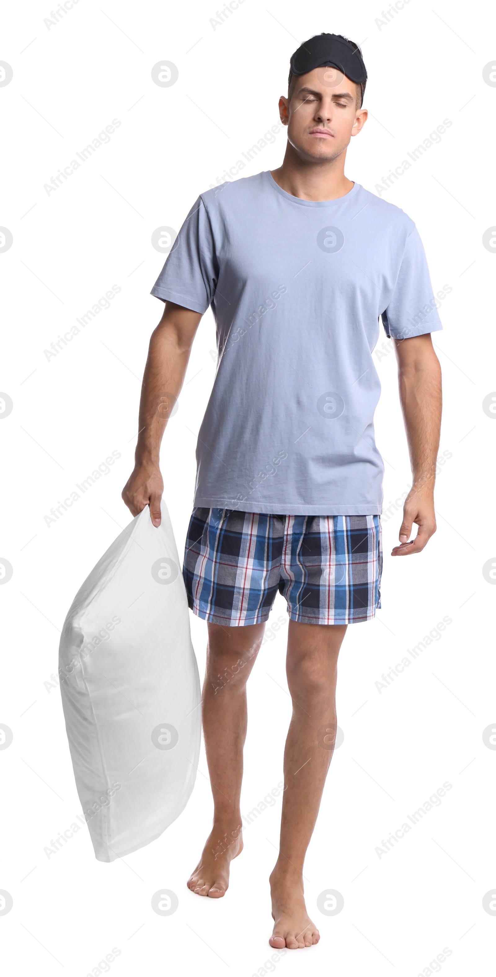 Photo of Somnambulist with blindfold and soft pillow on white background. Sleepwalking