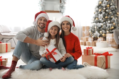Photo of Portrait of happy family with Christmas gifts on floor at home