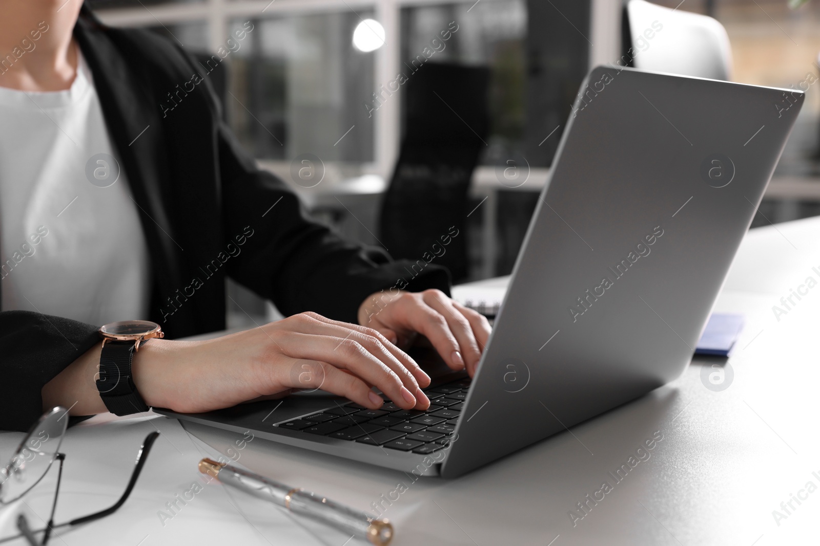 Photo of Woman working with laptop at white desk in office, closeup