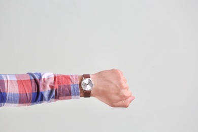 Photo of Young man with wristwatch on grey background. Time concept