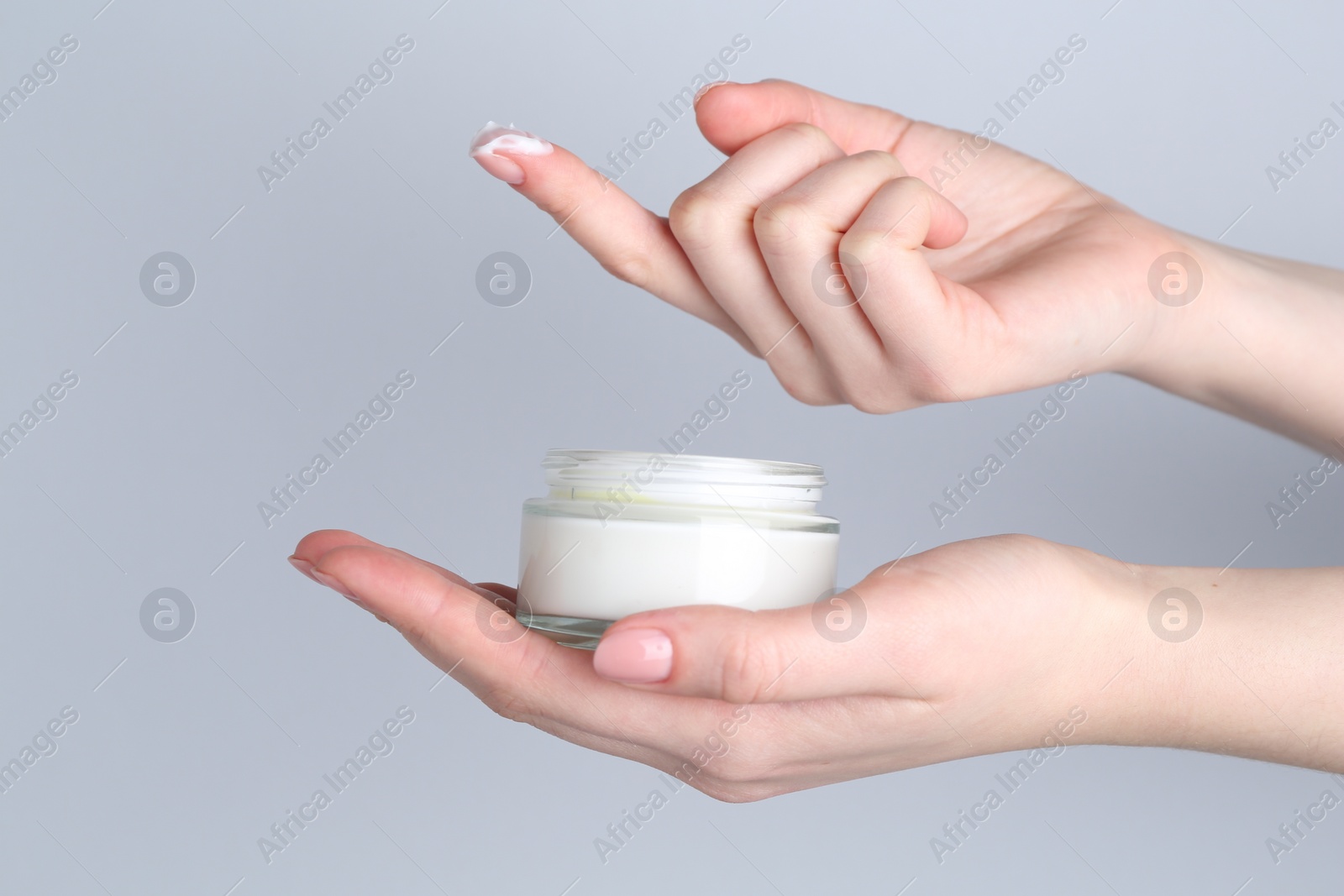 Photo of Woman with jar of cream on grey background, closeup