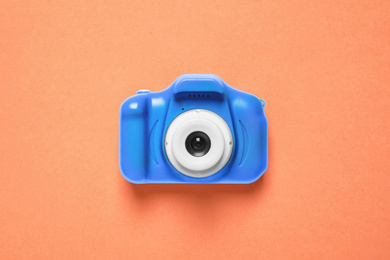 Photo of Toy camera on orange background, top view. Color of the year 2020 (Classic blue)