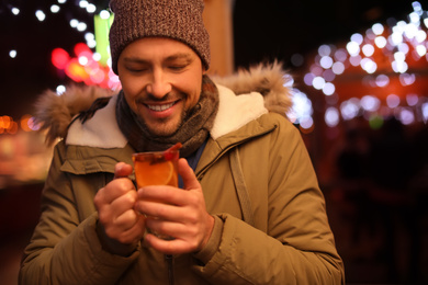 Happy man with mulled wine at winter fair