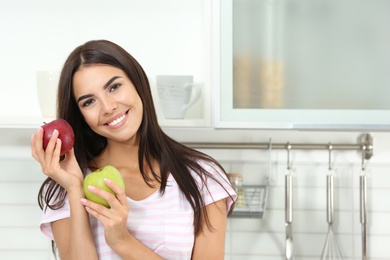 Photo of Happy woman holding fresh apples in kitchen. Space for text