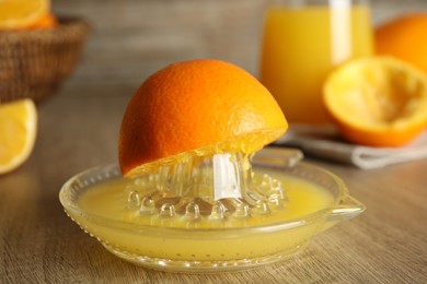 Squeezer and cut fresh oranges on wooden table, closeup