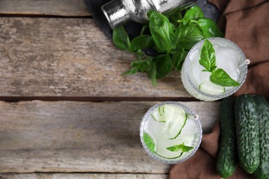 Glasses of refreshing cucumber water with basil on wooden table, flat lay. Space for text