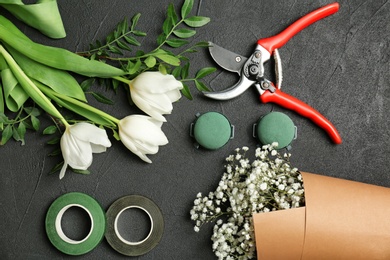Florist equipment with flowers on dark background, top view