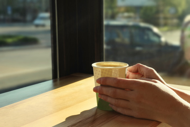 Photo of Woman with cup of fresh aromatic coffee at table in cafe