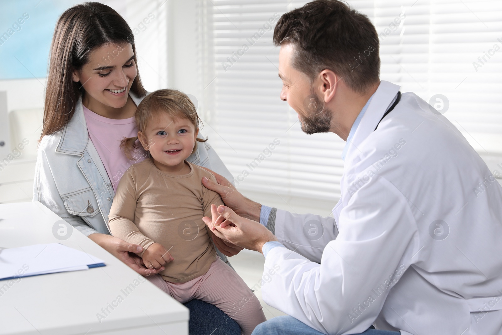 Photo of Mother and her cute baby having appointment with pediatrician in clinic. Doctor examining little girl