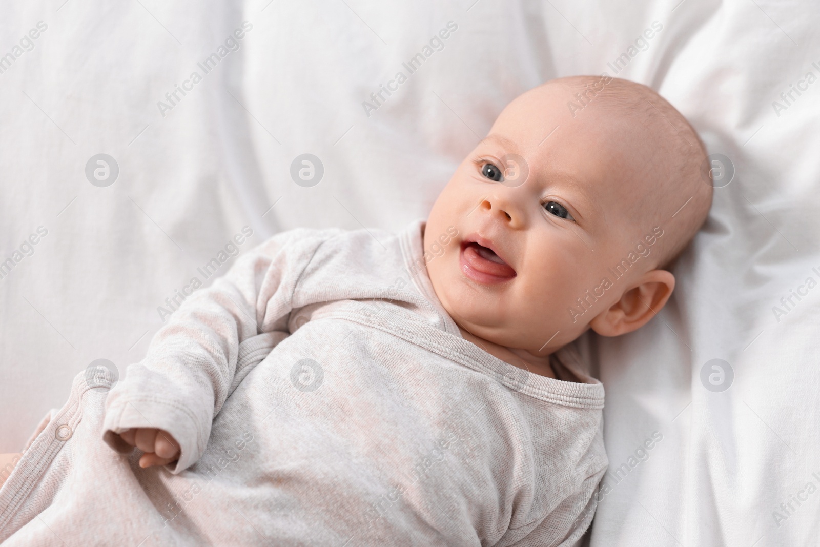 Photo of Cute little baby lying on white sheets