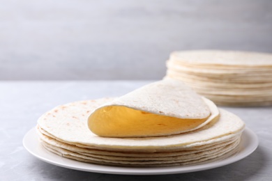 Photo of Plate with stack of tasty tortillas on grey table. Space for text
