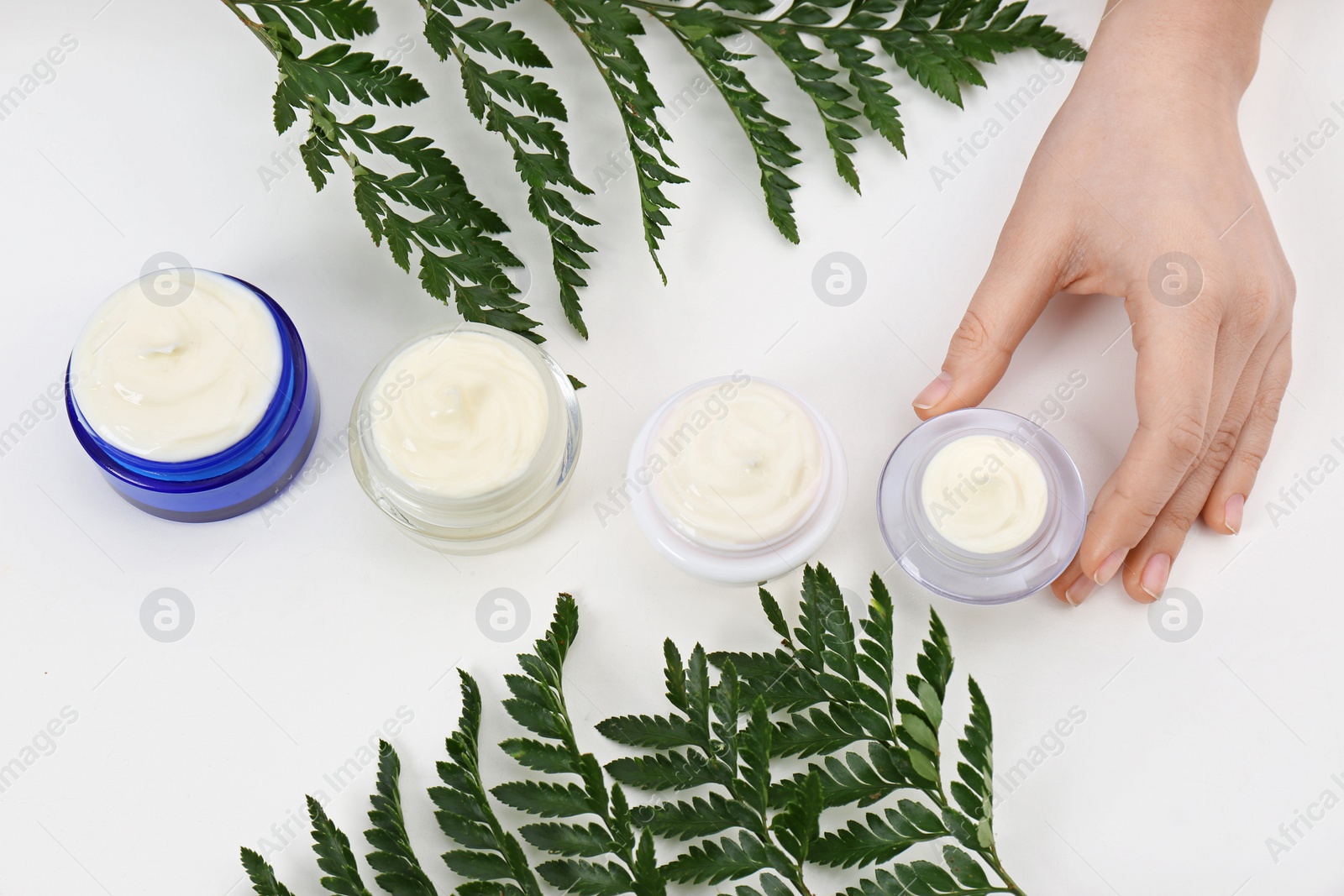Photo of Female dermatologist with jars of skin care products on white background, closeup