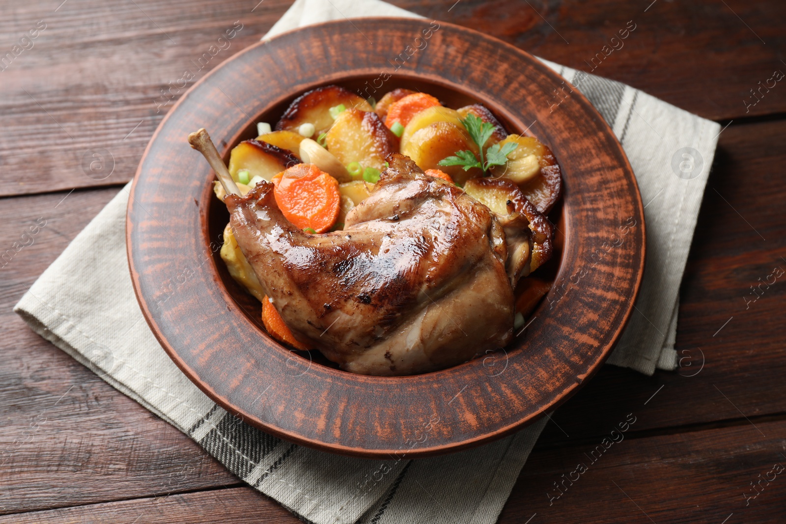 Photo of Tasty cooked rabbit meat with vegetables on wooden table, above view