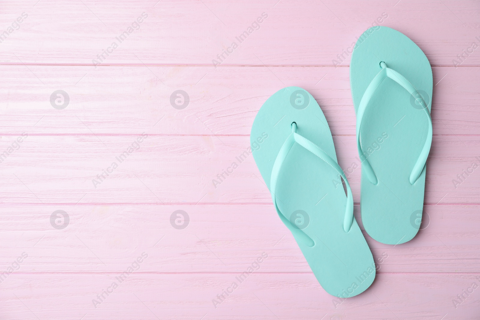 Photo of Flip flops and space for text on pink wooden background, top view. Beach objects