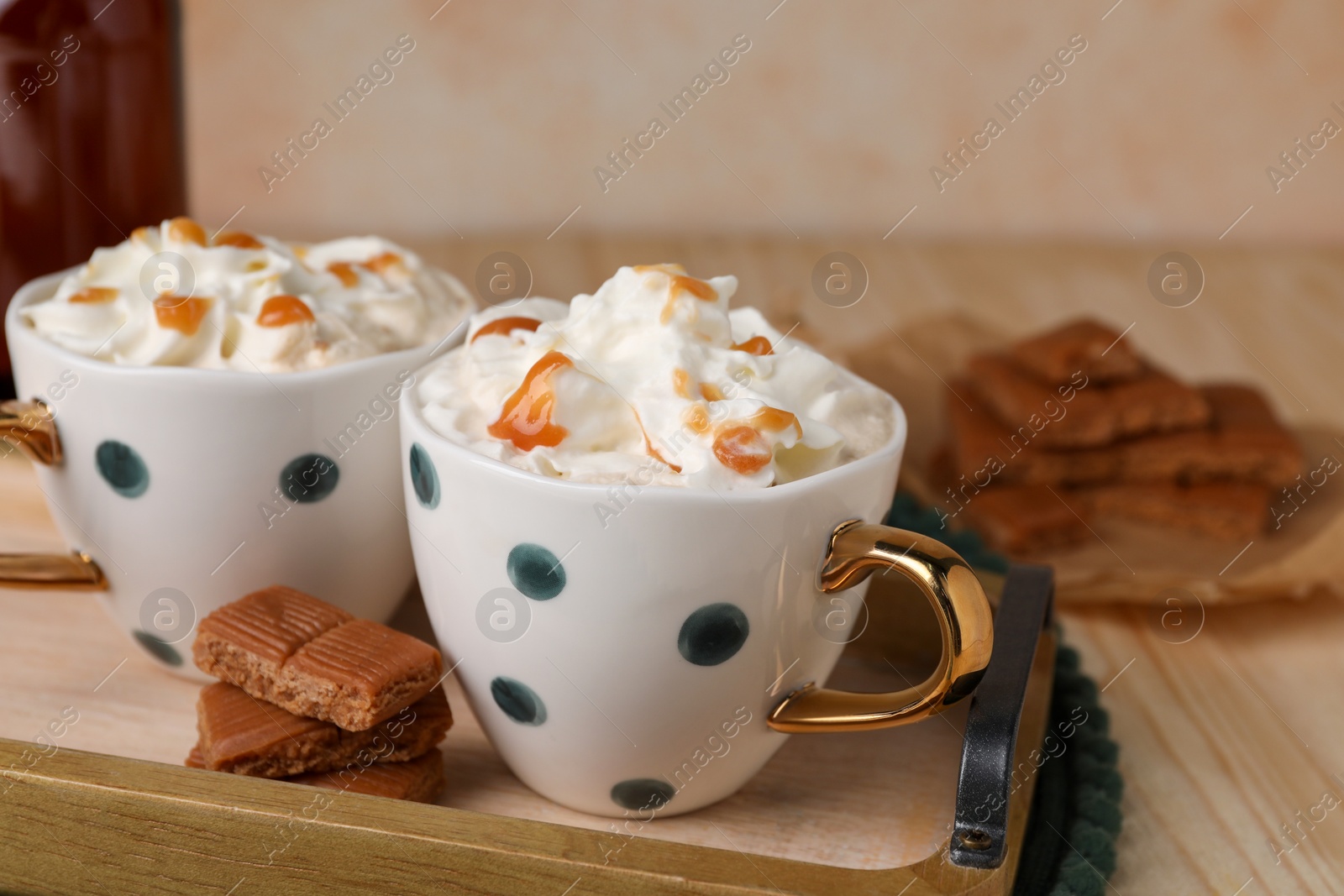 Photo of Delicious coffee with whipped cream and caramel syrup on wooden table, space for text