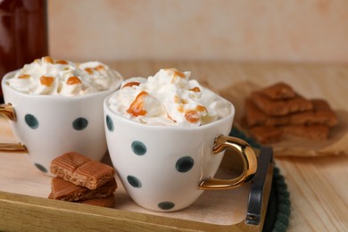 Delicious coffee with whipped cream and caramel syrup on wooden table, space for text