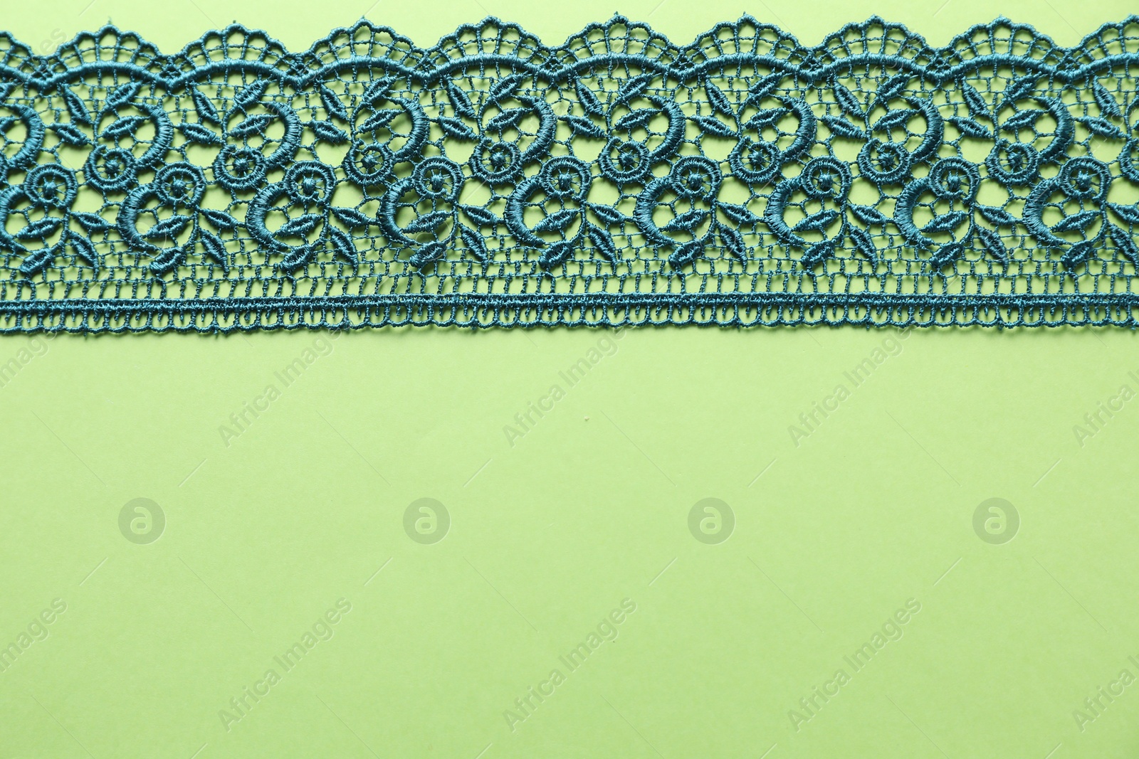 Photo of Beautiful lace on green background, top view. Space for text