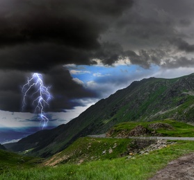 Image of Dark cloudy sky with lightning striking ground. Thunderstorm in mountains