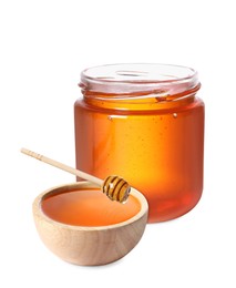 Natural honey dripping from dipper into wooden bowl. Jar full of honey on white background