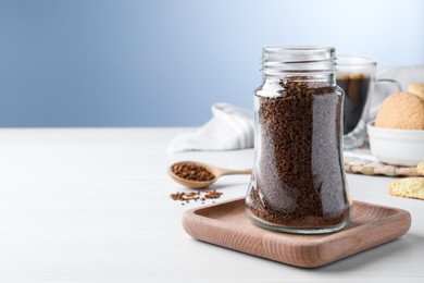 Photo of Jar of instant coffee on white wooden table. Space for text
