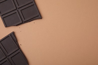 Pieces of chocolate bar on brown background, flat lay. Space for text